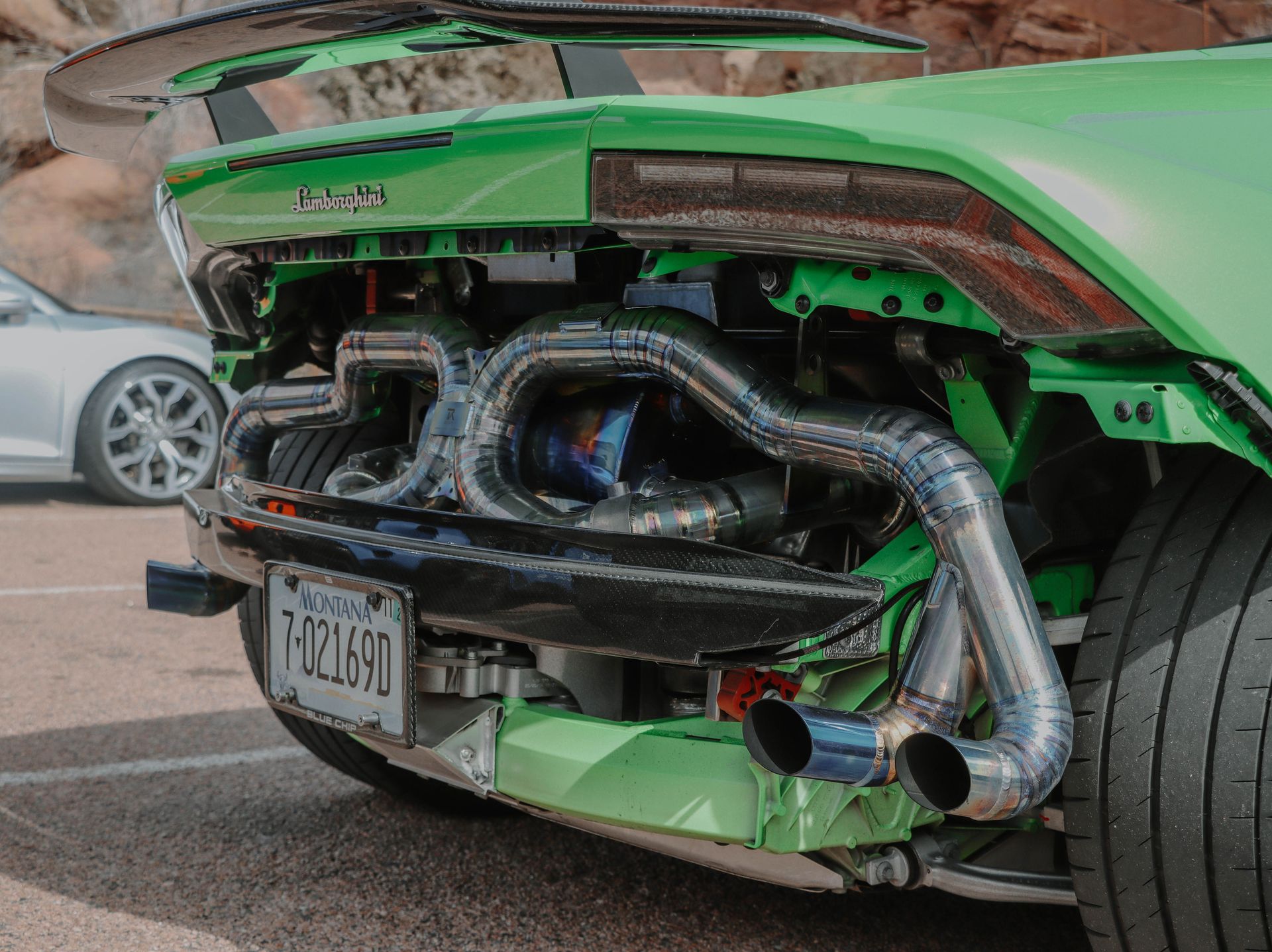 Detailed image showcasing the modified exhaust system of a Lamborghini Huracan parked outdoors.